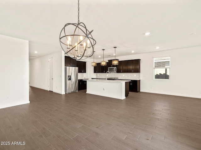 kitchen featuring a chandelier, hanging light fixtures, a center island with sink, appliances with stainless steel finishes, and sink