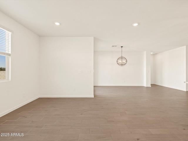 unfurnished room with a notable chandelier and wood-type flooring