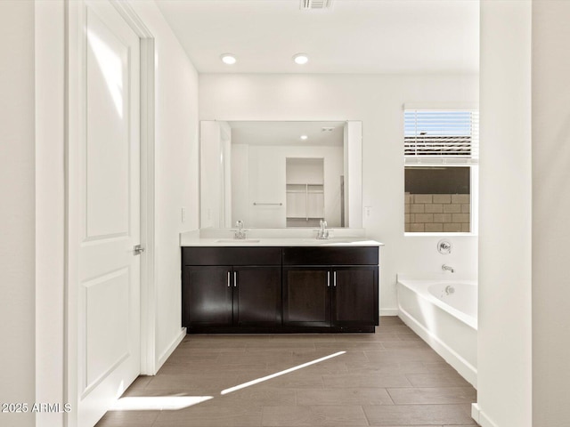 bathroom featuring a washtub and vanity