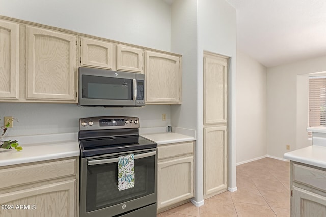 kitchen with light brown cabinetry, stainless steel appliances, and light tile patterned floors