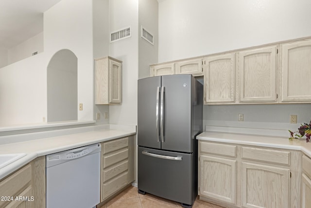 kitchen featuring white dishwasher, light brown cabinets, and stainless steel refrigerator