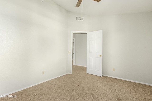 empty room with a high ceiling, light carpet, and ceiling fan