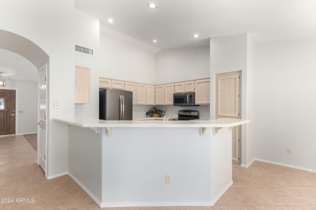 kitchen with appliances with stainless steel finishes, kitchen peninsula, high vaulted ceiling, and light tile patterned floors