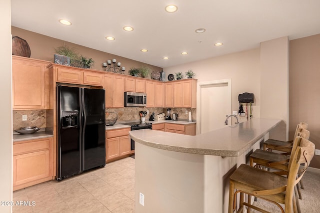 kitchen with kitchen peninsula, decorative backsplash, light brown cabinetry, and black appliances