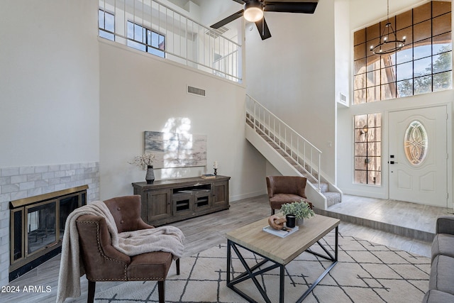 living room with light hardwood / wood-style flooring, a notable chandelier, a fireplace, and a high ceiling