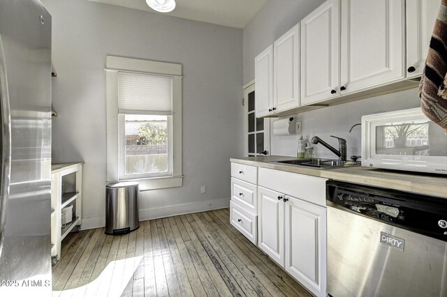 kitchen with white cabinetry, appliances with stainless steel finishes, sink, and light hardwood / wood-style flooring