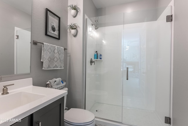 bathroom with a shower with shower door, toilet, and vanity