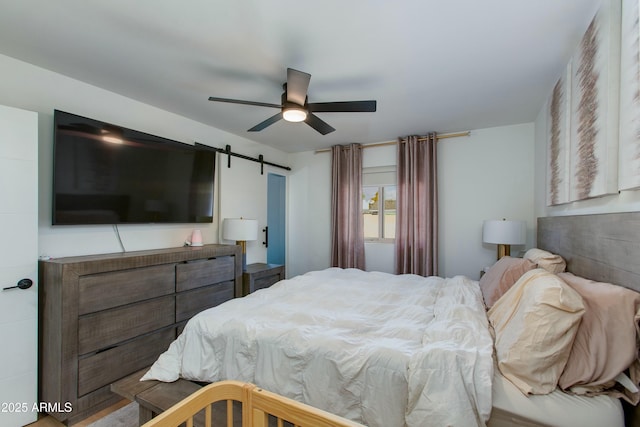 bedroom with a barn door and a ceiling fan