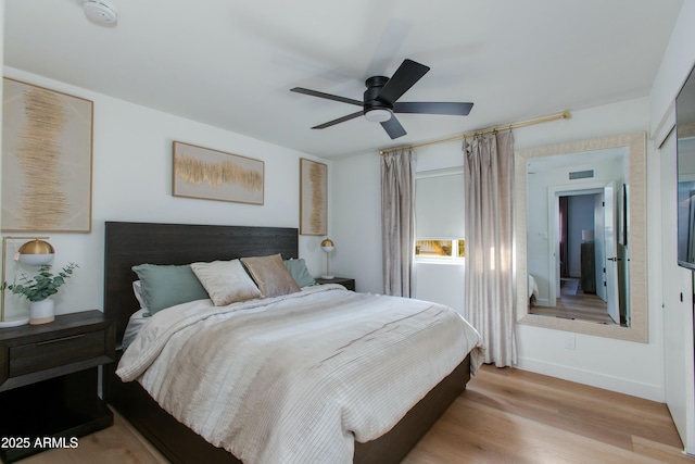 bedroom with a ceiling fan, visible vents, baseboards, and wood finished floors