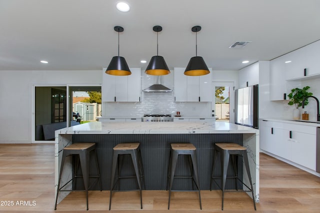 kitchen featuring light wood-style floors, freestanding refrigerator, white cabinetry, and visible vents