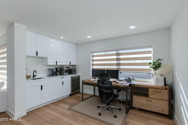 office with wine cooler, light wood-type flooring, a sink, and recessed lighting