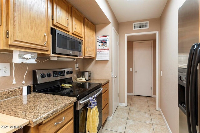 kitchen featuring light stone countertops, light tile patterned flooring, and stainless steel appliances