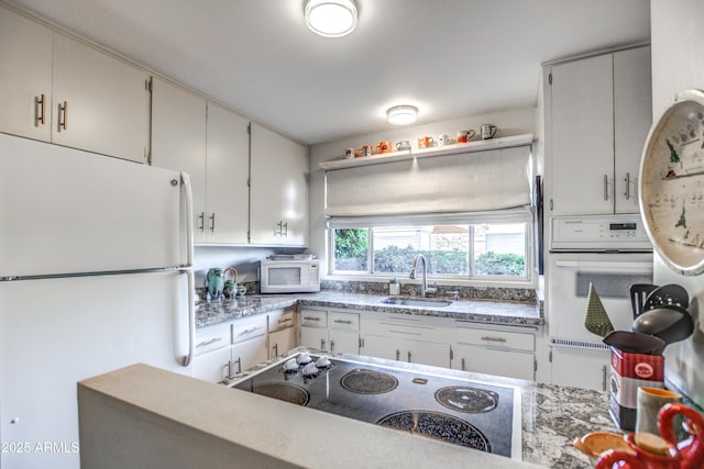 kitchen with sink, white appliances, and white cabinetry