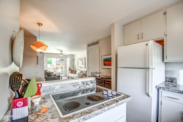 kitchen with ceiling fan, white refrigerator, white cabinets, cooktop, and light stone countertops