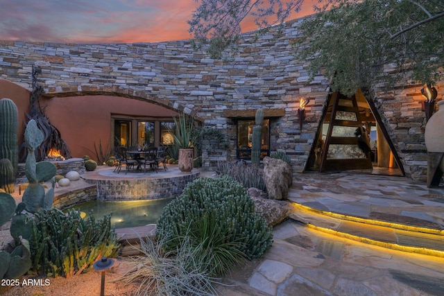 back house at dusk featuring a patio area