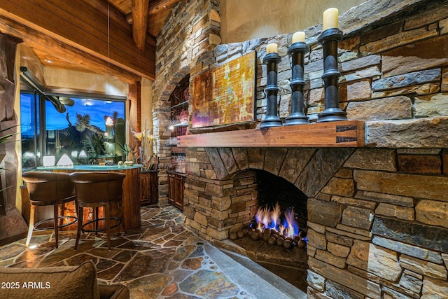 bar with beamed ceiling and an outdoor stone fireplace