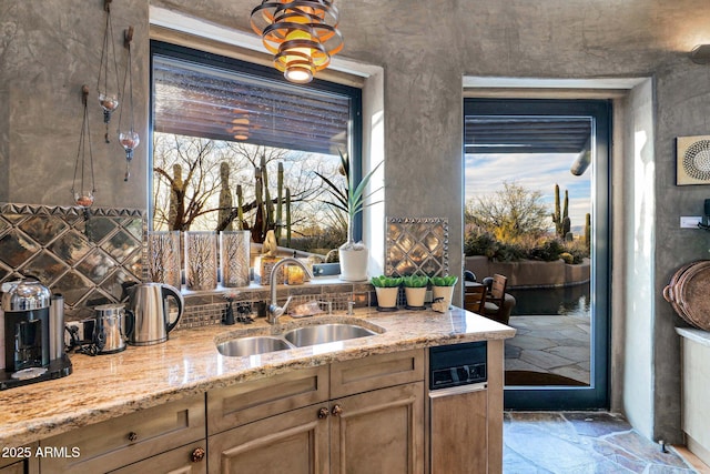 kitchen with sink, light stone counters, and decorative backsplash