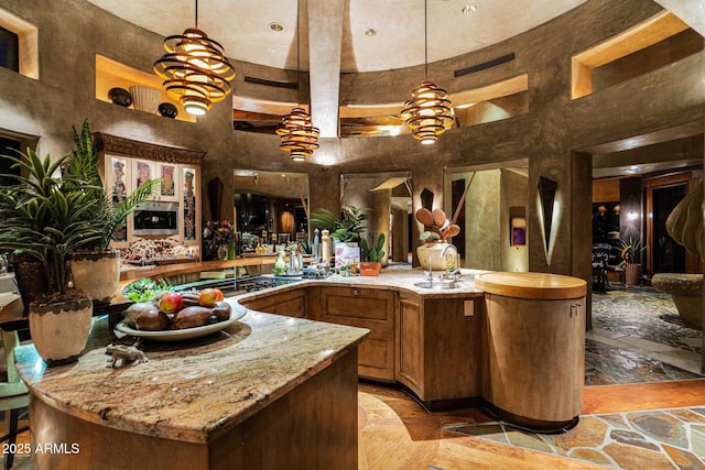 interior space featuring hanging light fixtures, a towering ceiling, and black gas stovetop