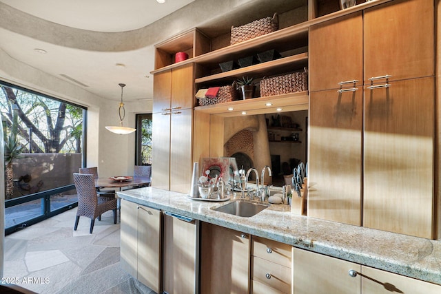 kitchen featuring light stone countertops, sink, and hanging light fixtures