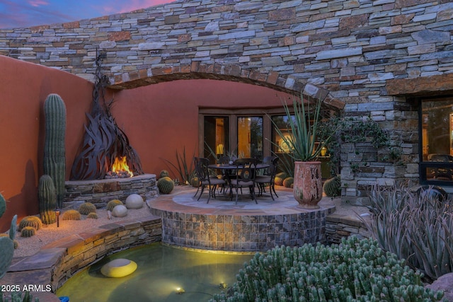 patio terrace at dusk featuring an outdoor fire pit