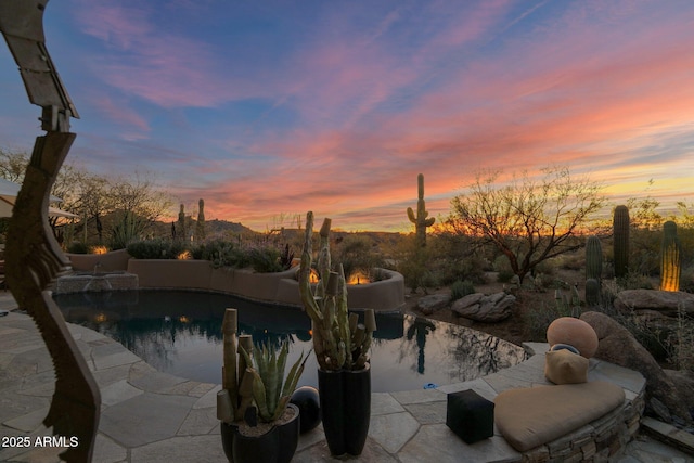 pool at dusk featuring a patio