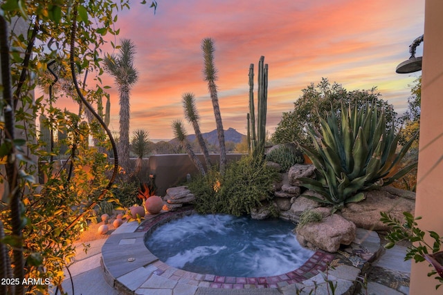 patio terrace at dusk featuring an in ground hot tub and a mountain view