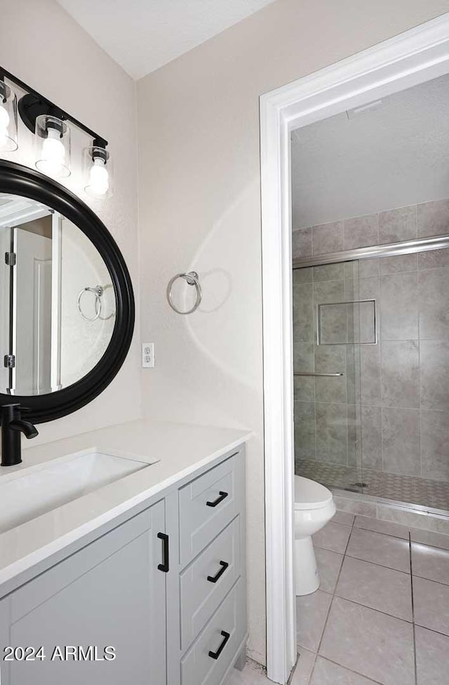 bathroom with tile patterned floors, vanity, toilet, and a shower with shower door