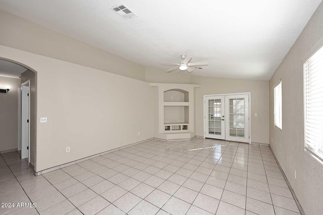 unfurnished living room featuring ceiling fan, french doors, built in features, lofted ceiling, and light tile patterned floors