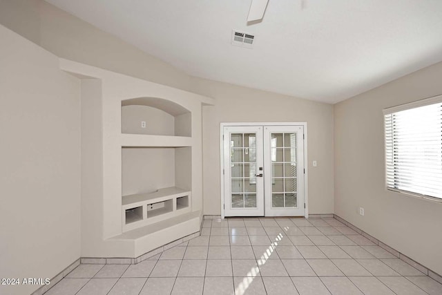 spare room featuring built in shelves, lofted ceiling, light tile patterned floors, and french doors