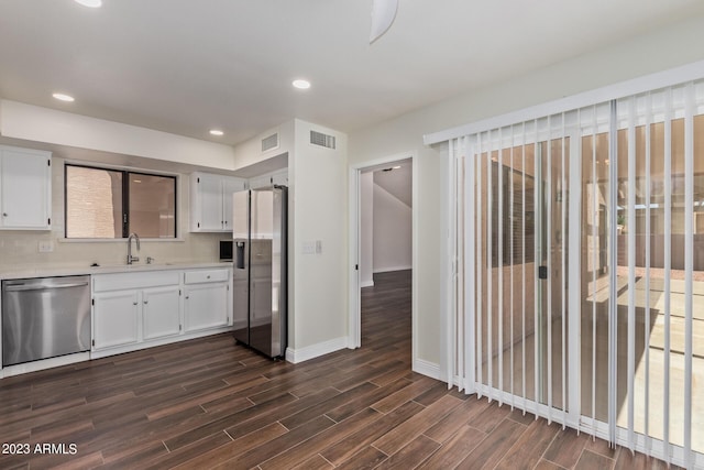 kitchen with appliances with stainless steel finishes, visible vents, dark wood finished floors, and a sink