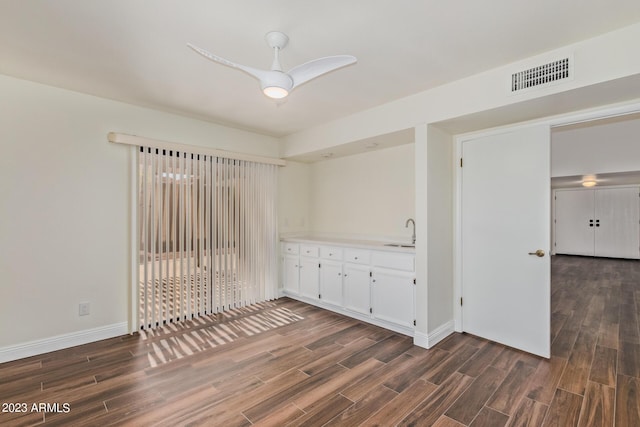 unfurnished room with baseboards, visible vents, dark wood-type flooring, and a sink