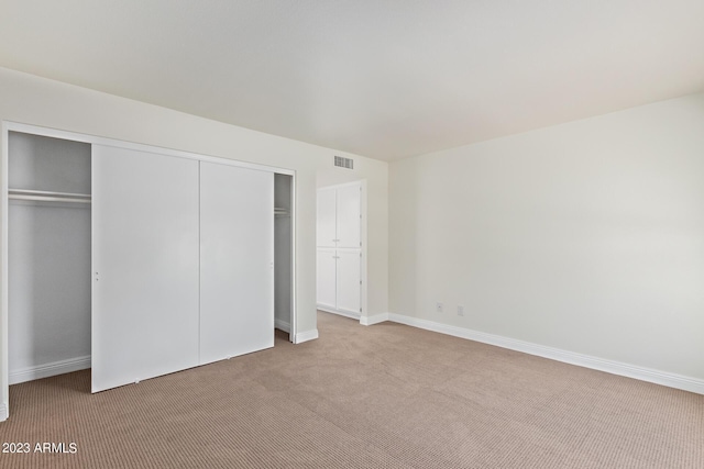 unfurnished bedroom featuring baseboards, visible vents, a closet, and carpet