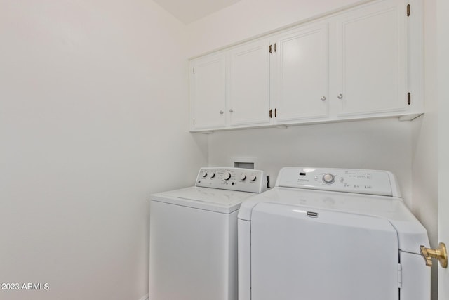 clothes washing area featuring washer and clothes dryer and cabinet space