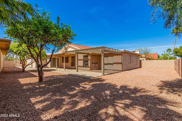 rear view of house with stucco siding, a tiled roof, a patio, and a fenced backyard