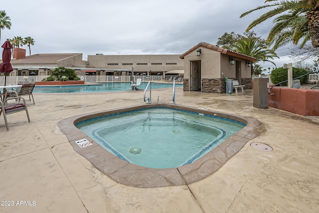 community pool featuring fence, a patio area, and a hot tub