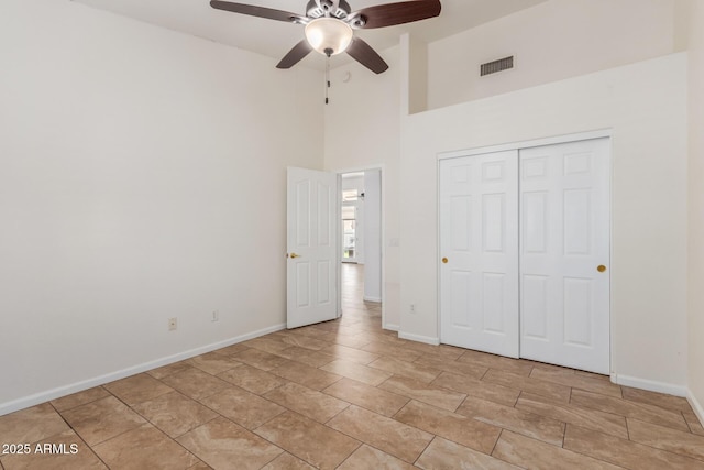 unfurnished bedroom featuring a high ceiling, ceiling fan, and a closet