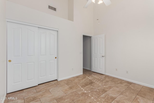 unfurnished bedroom with ceiling fan, a closet, and a high ceiling