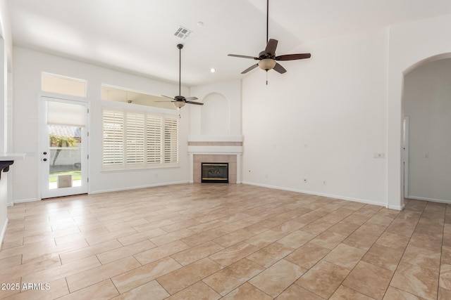 unfurnished living room featuring ceiling fan and a tile fireplace