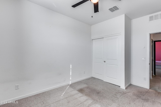 unfurnished bedroom featuring a closet, light colored carpet, and ceiling fan