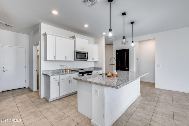 kitchen featuring a center island with sink, white cabinetry, appliances with stainless steel finishes, pendant lighting, and light stone countertops