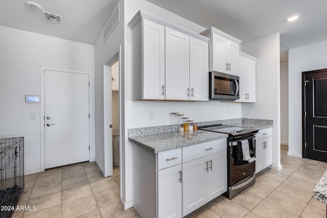 kitchen with white cabinets, light tile patterned floors, light stone counters, and appliances with stainless steel finishes