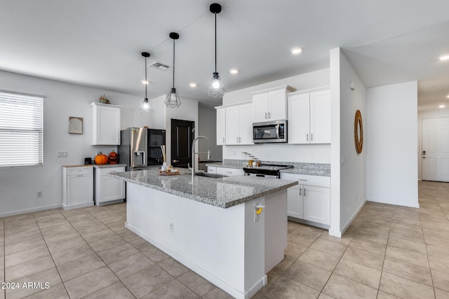 kitchen with light stone countertops, appliances with stainless steel finishes, an island with sink, and white cabinets