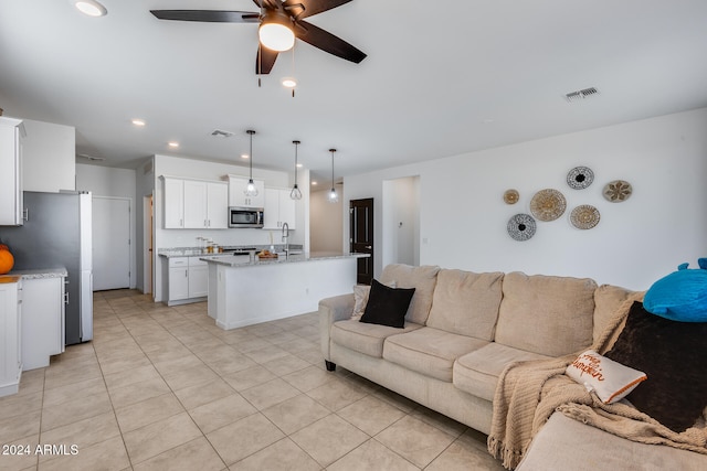 tiled living room with ceiling fan and sink