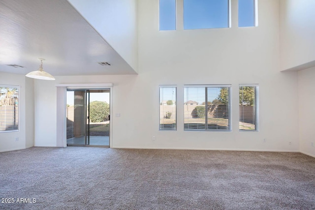 unfurnished living room with a towering ceiling and carpet