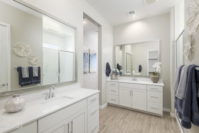 bathroom featuring an enclosed shower, vanity, and wood-type flooring