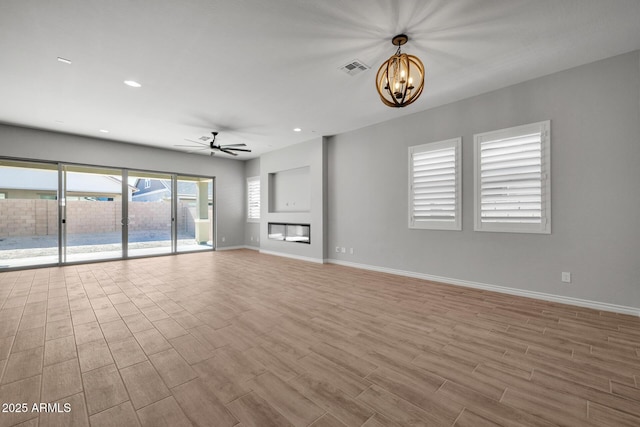 unfurnished living room featuring ceiling fan with notable chandelier