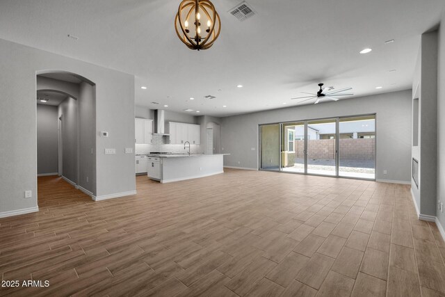 unfurnished living room with ceiling fan with notable chandelier