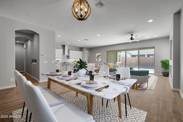 dining space with ceiling fan with notable chandelier