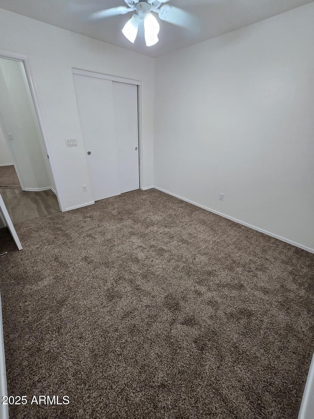 unfurnished bedroom with dark colored carpet, ceiling fan, and a closet