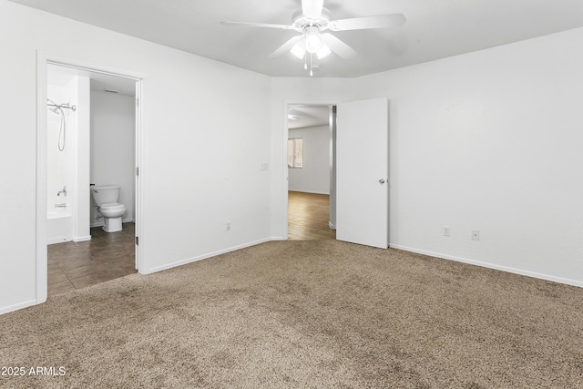 unfurnished bedroom featuring dark carpet, ceiling fan, and ensuite bathroom